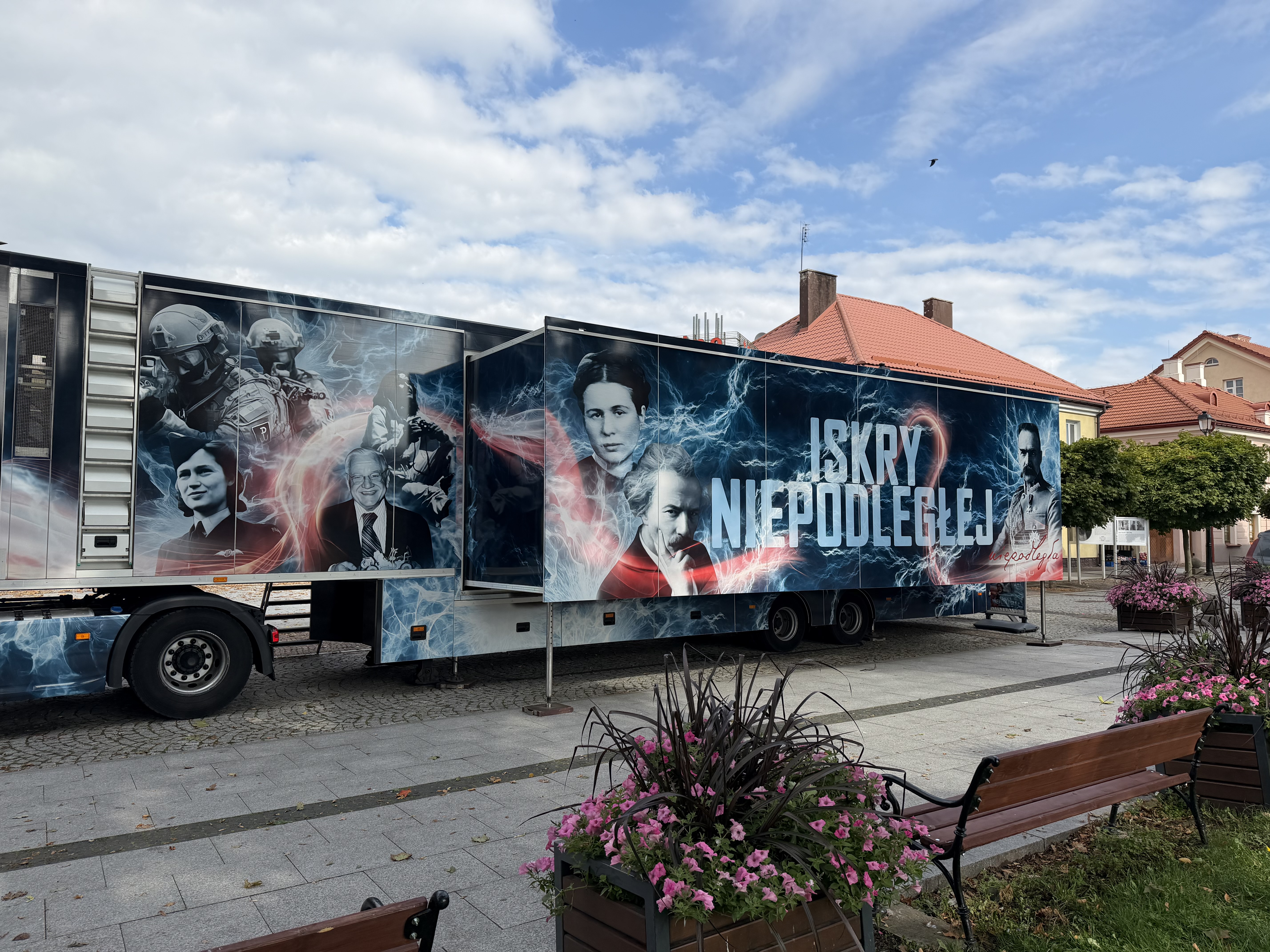 Mobilna wystawa &bdquo;Iskry Niepodległej&rdquo; ustawiona na&nbsp;placu w&nbsp;Sok&oacute;łce. Na pojeździe widoczne są portrety postaci historycznych oraz&nbsp;napis &bdquo;Iskry Niepodległej&rdquo;.