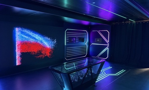 Wnętrze mobilnej wystawy „Iskry Niepodległej” z multimedialnymi ekranami, podświetlanymi instalacjami oraz ekspozycją w biało-czerwonych barwach.
